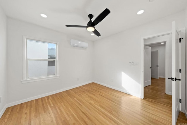 unfurnished room featuring light hardwood / wood-style floors, a wall mounted air conditioner, and ceiling fan