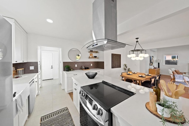 kitchen with pendant lighting, white cabinets, stainless steel appliances, decorative backsplash, and island range hood