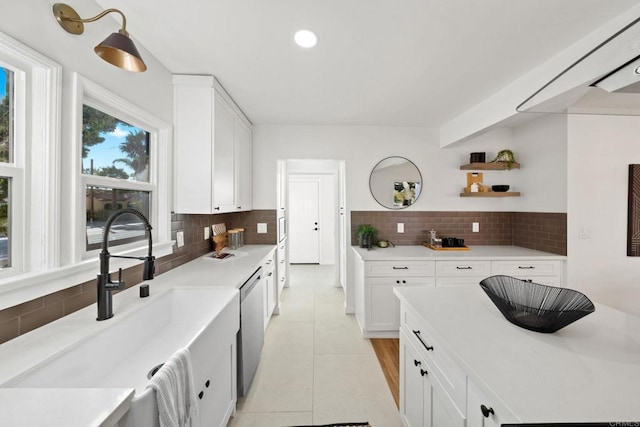 kitchen with sink, backsplash, white cabinets, and light tile patterned floors