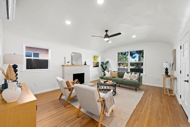 living room featuring brick ceiling, ceiling fan, a fireplace, light hardwood / wood-style floors, and lofted ceiling