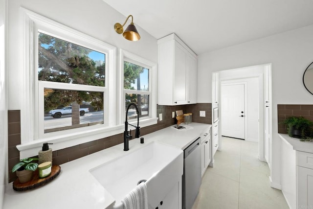 kitchen featuring tasteful backsplash, dishwasher, white cabinetry, light tile patterned floors, and sink