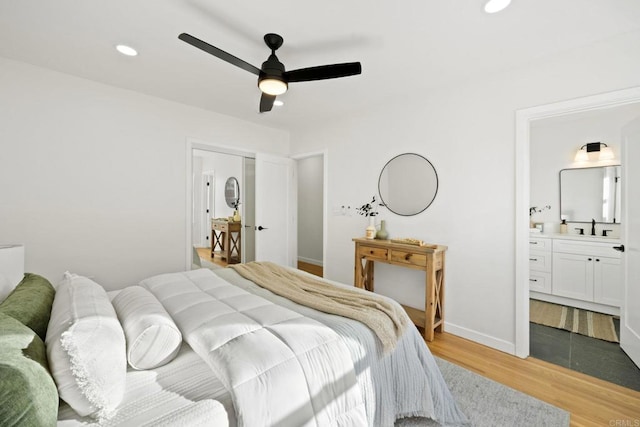 bedroom featuring sink, hardwood / wood-style flooring, ensuite bath, and ceiling fan