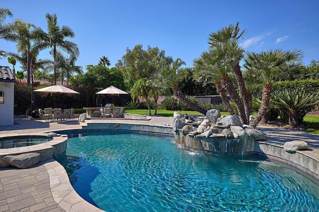 view of pool with an in ground hot tub, pool water feature, exterior bar, and a patio area