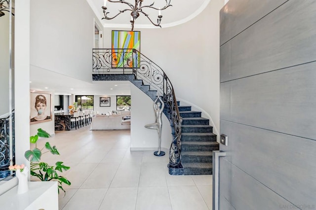 stairway with tile patterned floors, crown molding, a high ceiling, and an inviting chandelier