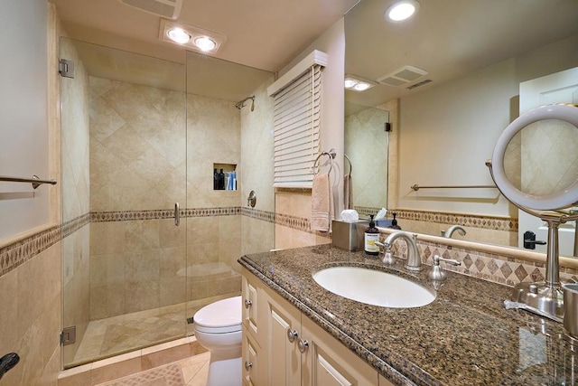 bathroom featuring walk in shower, tile patterned floors, toilet, vanity, and tile walls