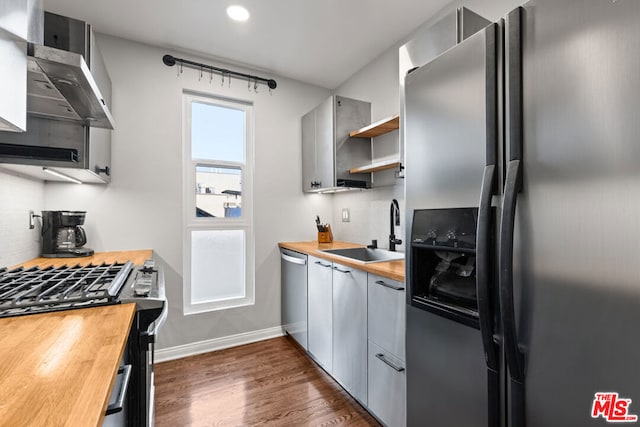 kitchen featuring dark hardwood / wood-style floors, stainless steel appliances, tasteful backsplash, wooden counters, and sink