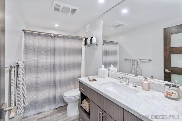 bathroom with hardwood / wood-style floors, vanity, toilet, and a shower with curtain