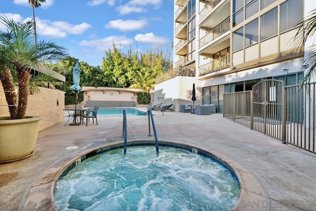 view of swimming pool featuring a community hot tub and a patio