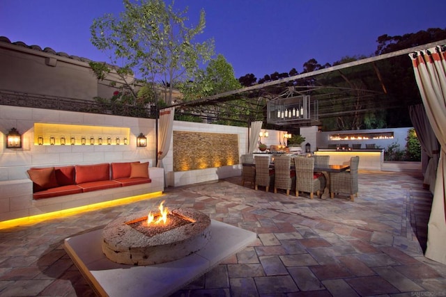 patio terrace at dusk with an outdoor living space with a fireplace