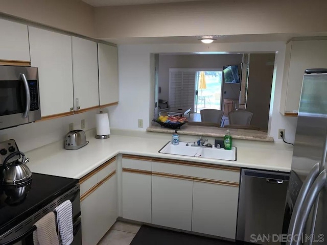 kitchen with white cabinetry, sink, kitchen peninsula, and appliances with stainless steel finishes