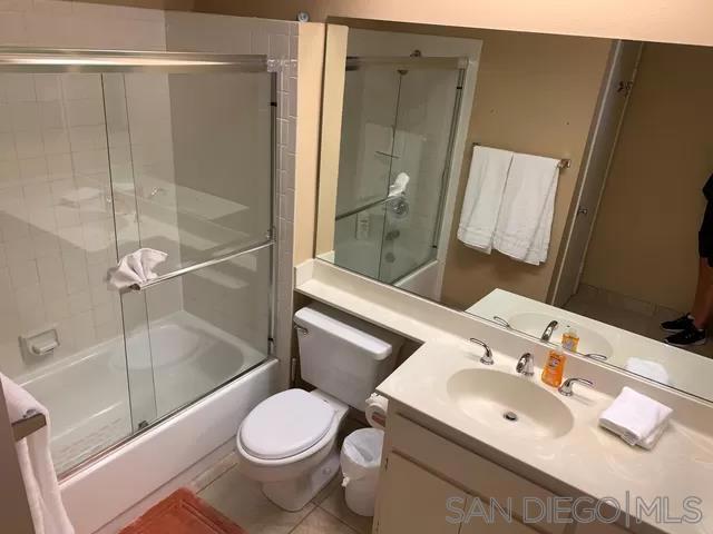 full bathroom with tile patterned flooring, enclosed tub / shower combo, vanity, and toilet