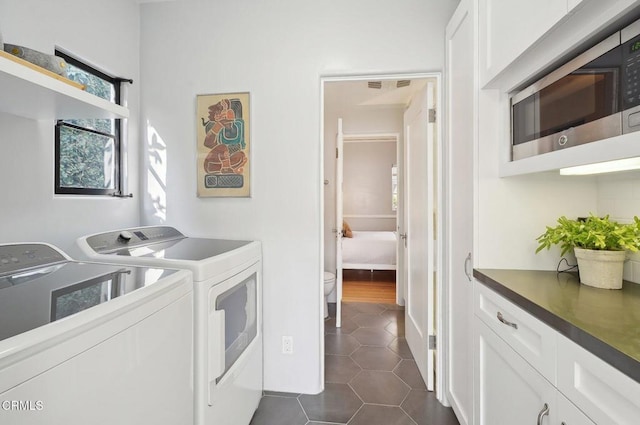 laundry area with washer and dryer, cabinets, and dark tile patterned floors