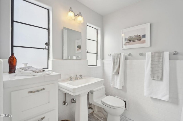 bathroom with tile patterned flooring, tile walls, and toilet