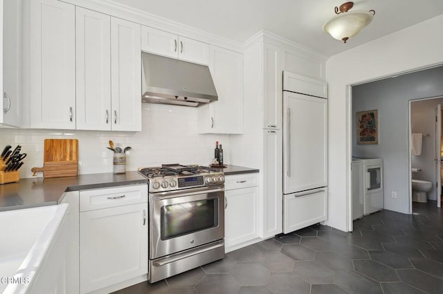 kitchen with dark tile patterned flooring, high quality appliances, white cabinetry, and tasteful backsplash