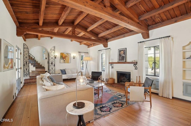 living room featuring beam ceiling, light wood-type flooring, wooden ceiling, and high vaulted ceiling