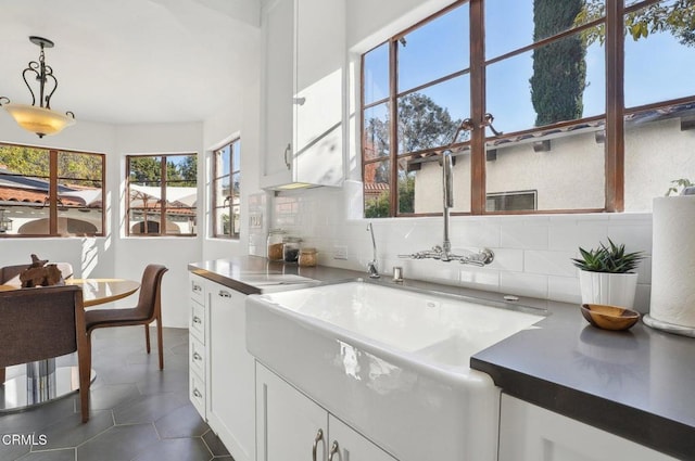 kitchen with decorative light fixtures, dark tile patterned floors, white cabinetry, and tasteful backsplash