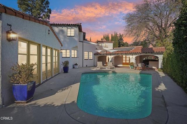 pool at dusk with a patio area