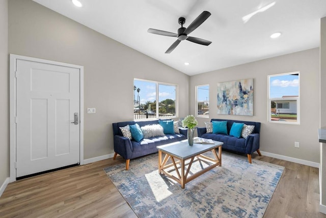 living room with ceiling fan, light hardwood / wood-style flooring, and vaulted ceiling