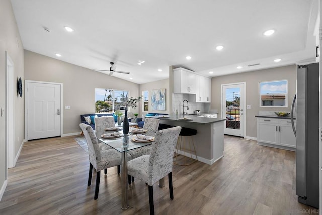 dining area with ceiling fan, light hardwood / wood-style floors, sink, and vaulted ceiling