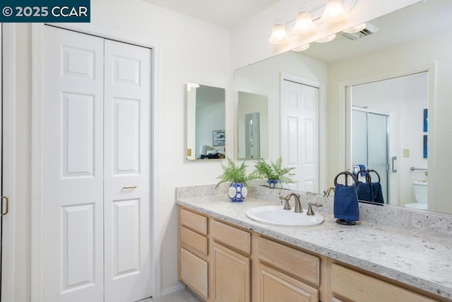 bathroom with vanity, a shower with shower door, and toilet