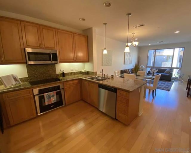 kitchen featuring kitchen peninsula, sink, light wood-type flooring, and appliances with stainless steel finishes