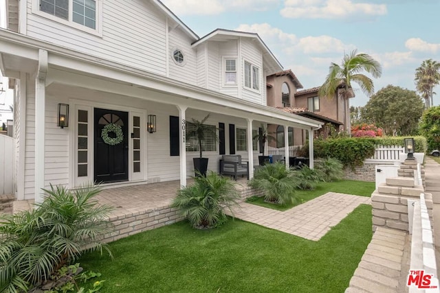 rear view of property featuring a porch and a yard