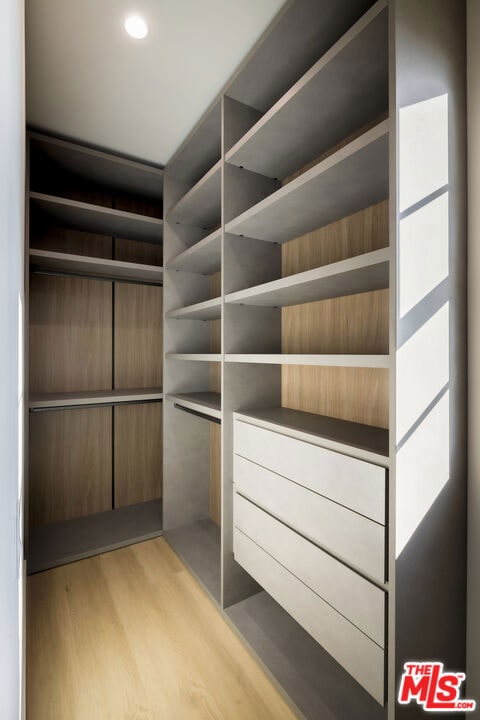 walk in closet with light hardwood / wood-style floors