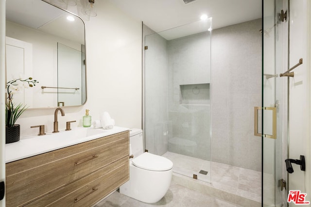 bathroom with tile patterned floors, vanity, toilet, and a shower with door