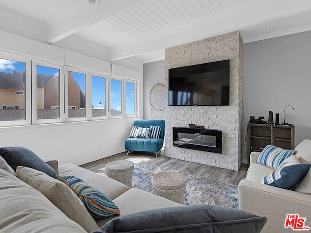 living room featuring hardwood / wood-style floors, wooden ceiling, a stone fireplace, ornamental molding, and beam ceiling