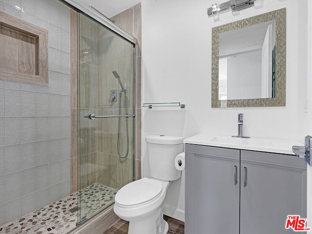 bathroom featuring vanity, toilet, and a shower with shower door