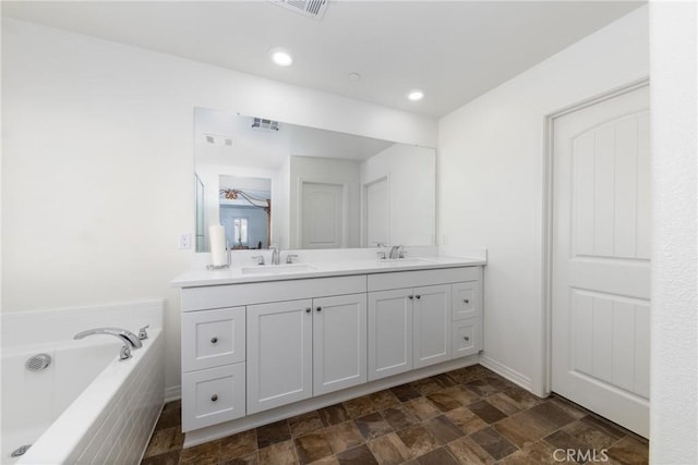 bathroom featuring vanity and tiled tub