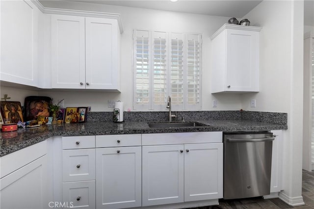 kitchen featuring stainless steel dishwasher, sink, dark stone countertops, and white cabinetry