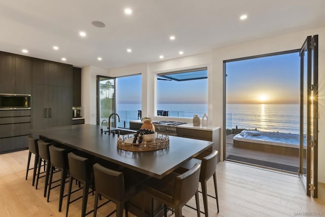 dining area with light wood-type flooring, a water view, and sink