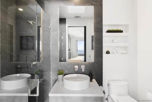 bathroom with vanity, backsplash, toilet, walk in shower, and tile walls