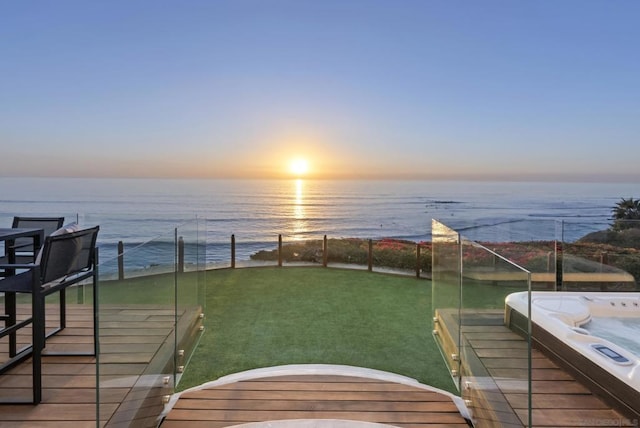 yard at dusk featuring an outdoor hot tub and a water view