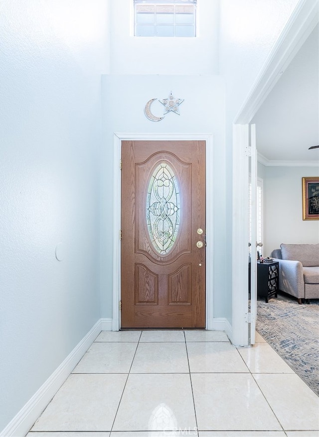 foyer entrance with light tile patterned flooring and ornamental molding