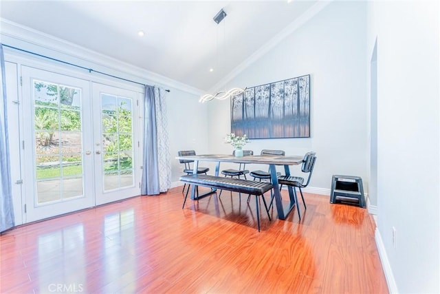 dining room featuring hardwood / wood-style floors, vaulted ceiling, ornamental molding, and french doors