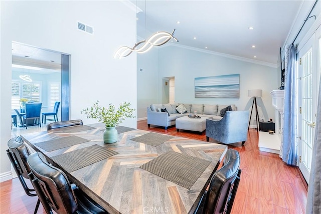 dining space featuring lofted ceiling, wood-type flooring, ornamental molding, and french doors