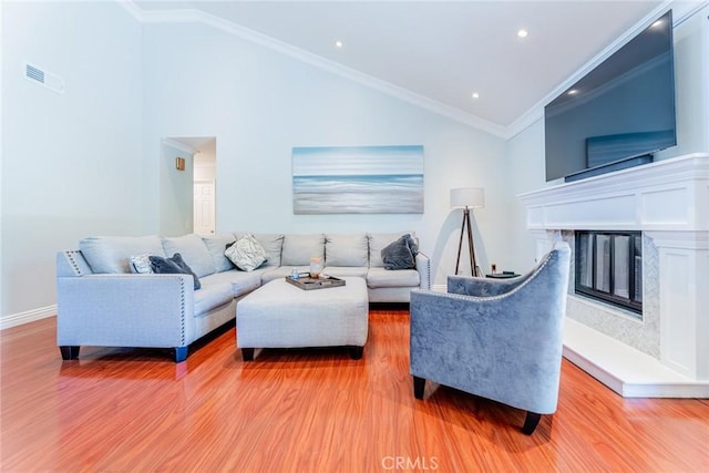 living room featuring a high end fireplace, lofted ceiling, light hardwood / wood-style floors, and crown molding