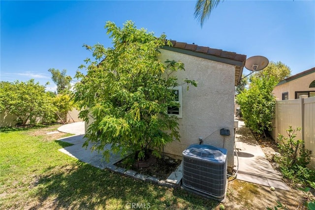 view of side of home with a lawn and central AC unit