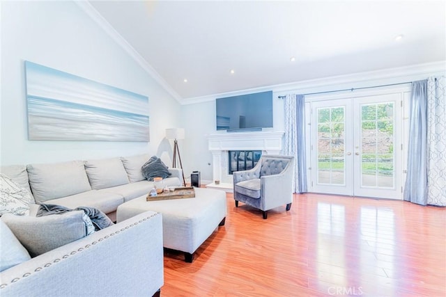 living room with french doors, light hardwood / wood-style floors, vaulted ceiling, and ornamental molding