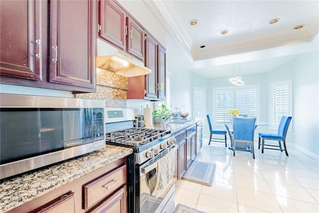 kitchen with a raised ceiling, hanging light fixtures, stainless steel appliances, and sink