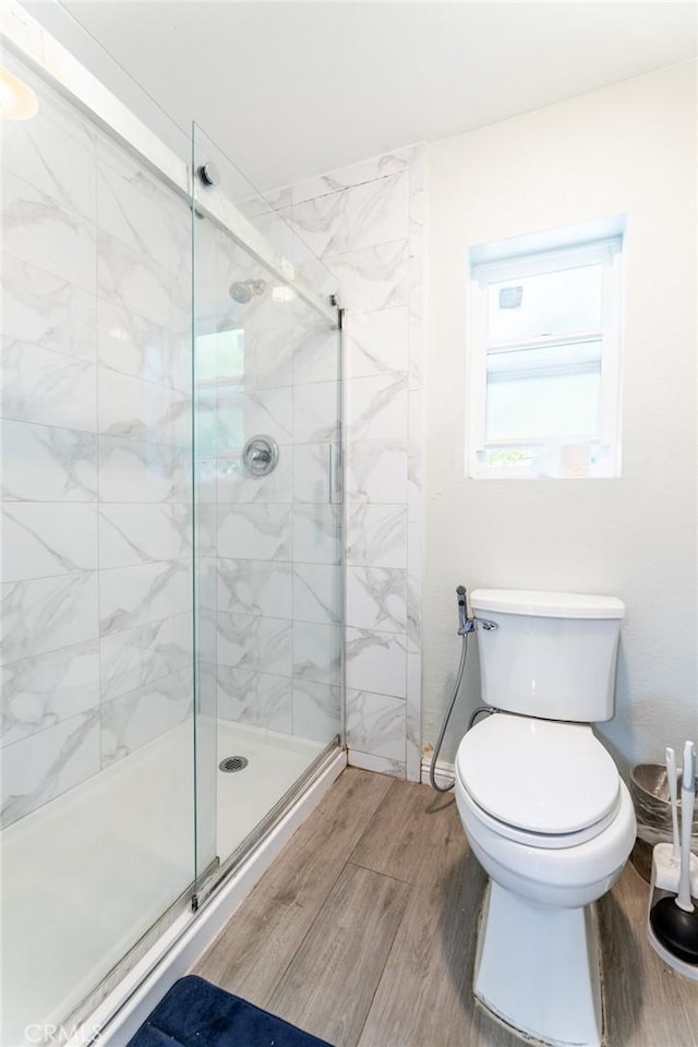 bathroom featuring toilet and a shower with shower door