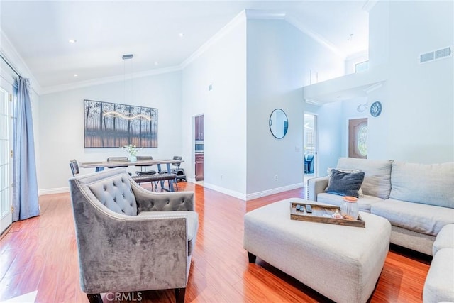 living room with hardwood / wood-style flooring, crown molding, and high vaulted ceiling