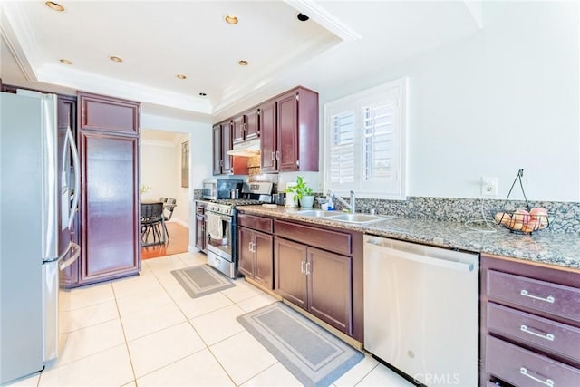 kitchen featuring sink, appliances with stainless steel finishes, a tray ceiling, light tile patterned floors, and ornamental molding