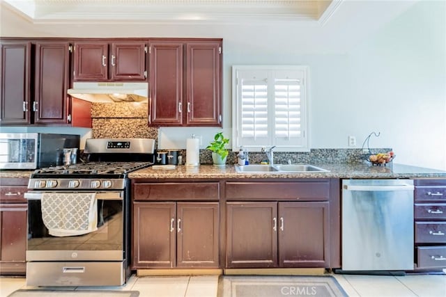 kitchen with sink, stainless steel appliances, a raised ceiling, light tile patterned flooring, and ornamental molding