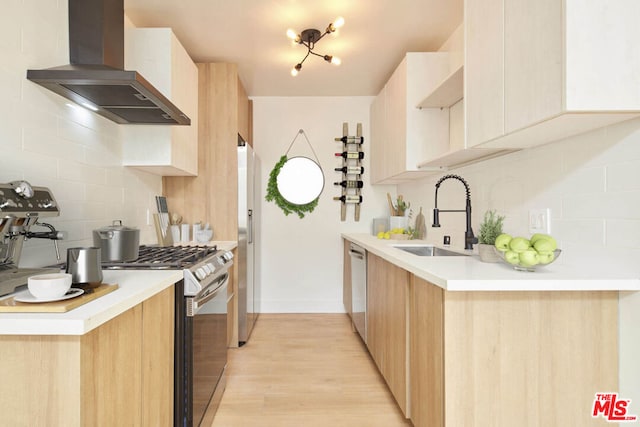 kitchen with light brown cabinetry, stainless steel appliances, wall chimney range hood, and sink