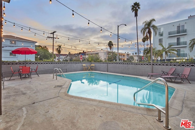 pool at dusk with a patio area