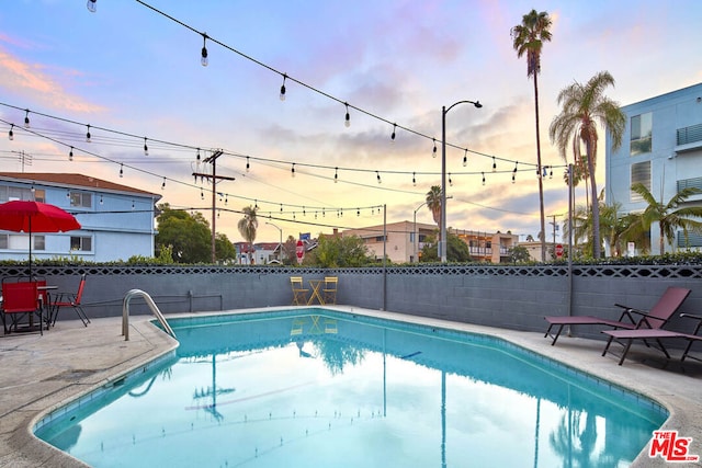 pool at dusk featuring a patio area