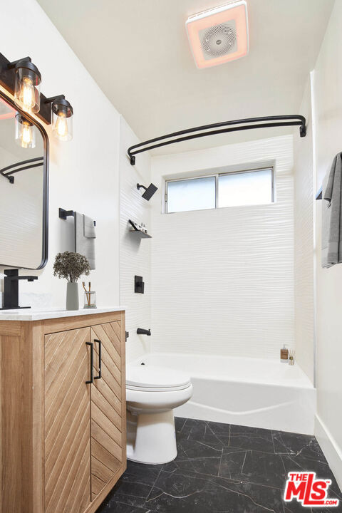 full bathroom featuring tiled shower / bath, vanity, and toilet